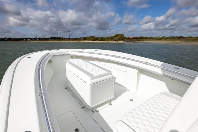 Slide: The Image of 2014 Yellowfin 32 Offshore boat with white seating, cruising near a scenic shoreline. - 9