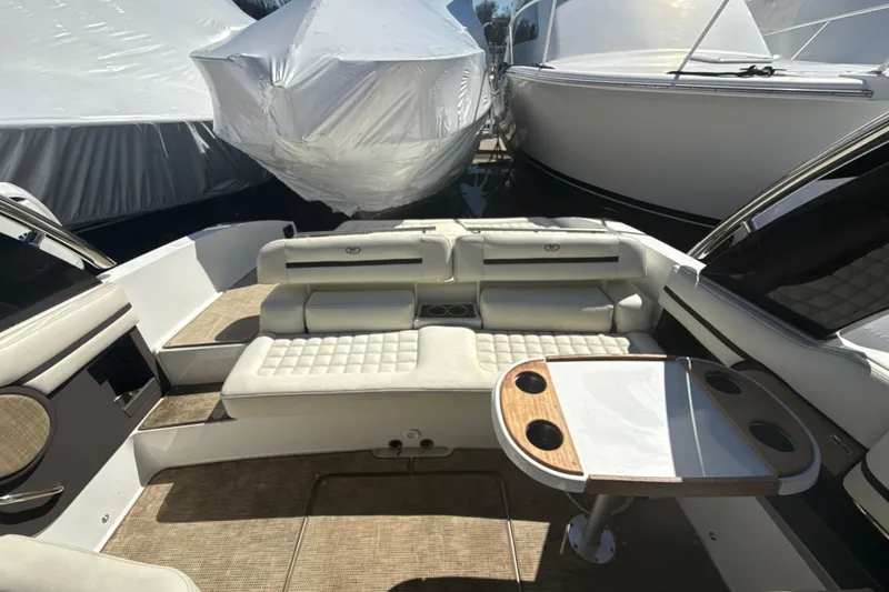 Slide: The Image of 2020 Cobalt R30 boat interior with cushioned seating and table, docked among covered boats. - 16