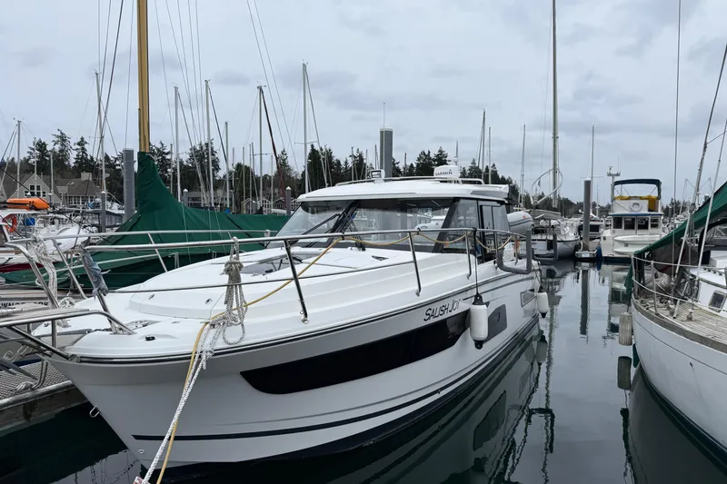 Slide: The Image of 2023 Jeanneau NC 1095 boat docked in a marina, surrounded by other vessels. - 1
