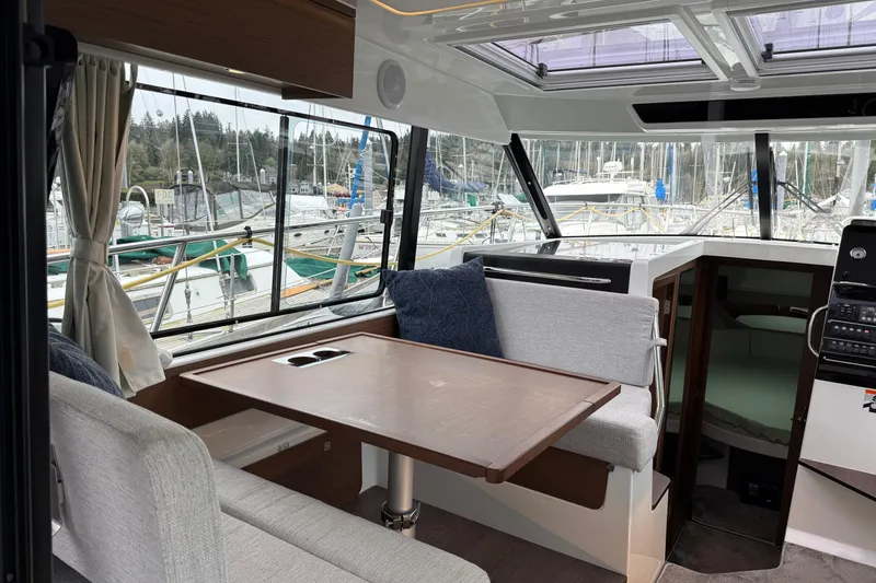 Slide: The Image of Interior of 2023 Jeanneau NC 1095 boat with dining area and marina view. - 10