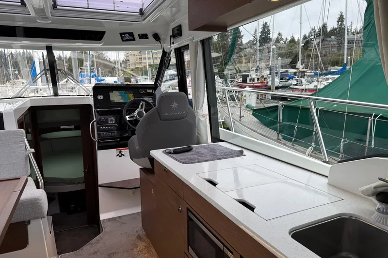 Slide: The Image of Interior of 2023 Jeanneau NC 1095 boat with helm, kitchen, and marina view. - 11