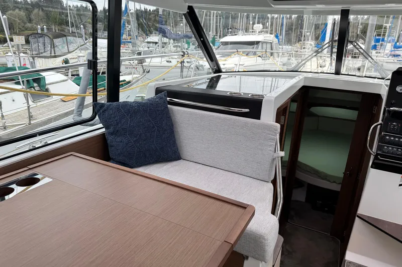 Slide: The Image of 2023 Jeanneau NC 1095 interior with seating, table, and marina view. - 13