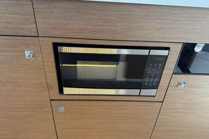 Slide: The Image of Built-in microwave in Jeanneau NC 1095, 2023 model, with sleek wood paneling. - 15