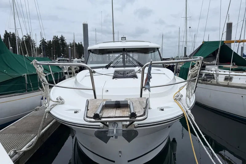 Slide: The Image of 2023 Jeanneau NC 1095 boat docked at marina, front view with ropes and railings. - 2