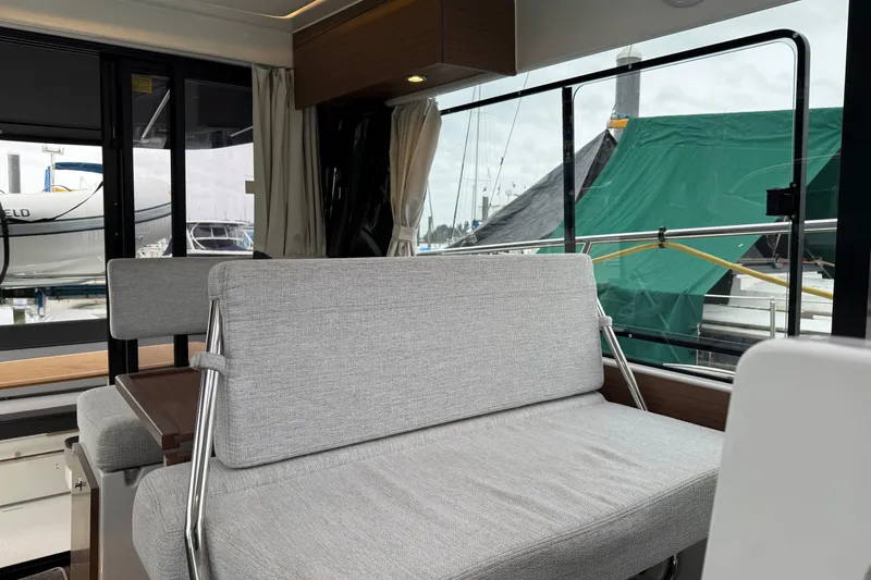 Slide: The Image of Interior of 2023 Jeanneau NC 1095 boat with gray seating and marina view. - 30