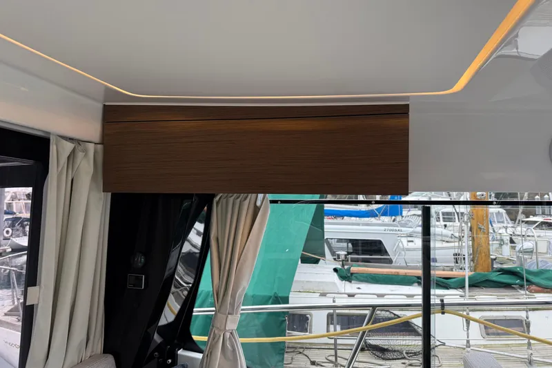Slide: The Image of Interior view of 2023 Jeanneau NC 1095 yacht with modern wood paneling and marina backdrop. - 34