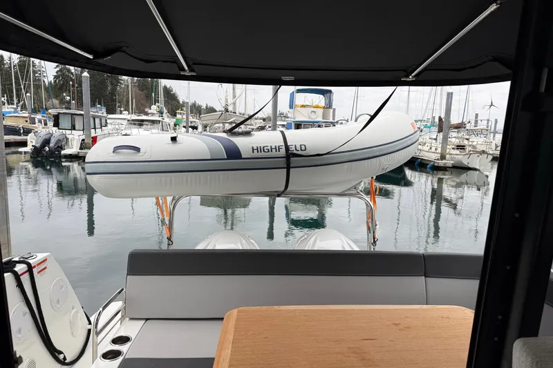 Slide: The Image of 2023 Jeanneau NC 1095 with dinghy at marina, viewed from cockpit. - 37