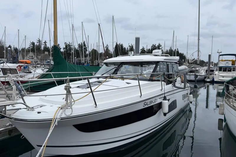 Slide: The Image of 2023 Jeanneau NC 1095 boat docked in a marina, surrounded by other vessels. - 42