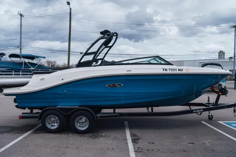 Slide: The Image of 2023 Sea Ray SPX 230 boat on trailer, blue hull, parked outdoors. - 2