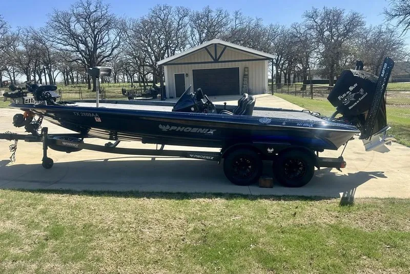 The Image of 2026 Phoenix 921 Elite X boat on trailer, parked in driveway near garage. - 1