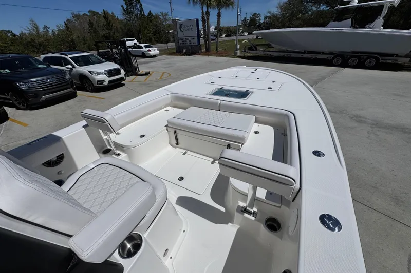 Slide: The Image of 2026 Sea Born FX25 Bay boat with white seating and spacious deck in a parking lot. - 16