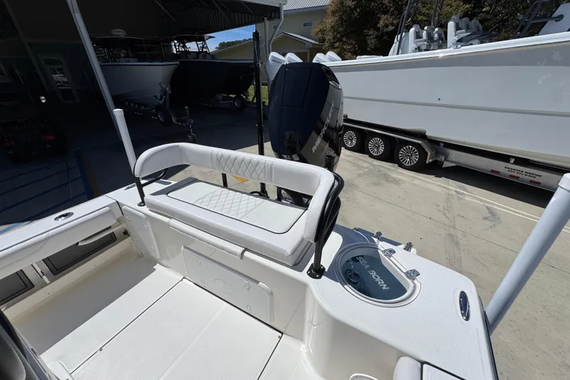 Slide: The Image of 2026 Sea Born FX25 Bay boat interior with seating and motor, parked in a marina. - 41