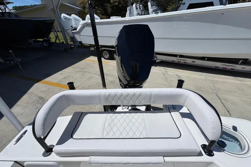 Slide: The Image of 2026 Sea Born FX25 Bay boat with cushioned seating and outboard motor in a marina. - 42