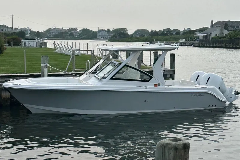 The Image of 2023 Edgewater 262CX Crossover boat docked by a scenic waterfront. - 0