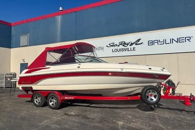 The Image of Red and white 2006 Bryant 219 boat on trailer, parked outside dealership. - 1