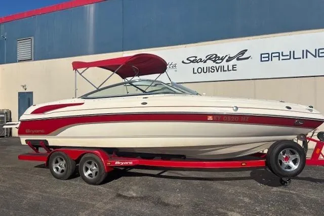 Slide: The Image of 2006 Bryant 219 boat with red accents on a trailer, parked outside a dealership. - 3