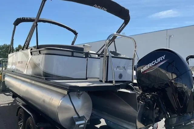 Slide: The Image of 2025 Avalon LSZ Quad Lounge pontoon boat with Mercury engine, parked outdoors. - 13