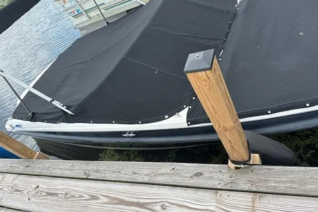 Slide: The Image of 2011 Bayliner 185 boat with black cover docked at a wooden pier. - 16