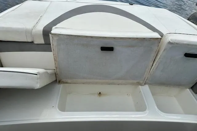 Slide: The Image of 2011 Bayliner 185 boat interior storage compartment with open hatch, showing seating and water backdrop. - 8