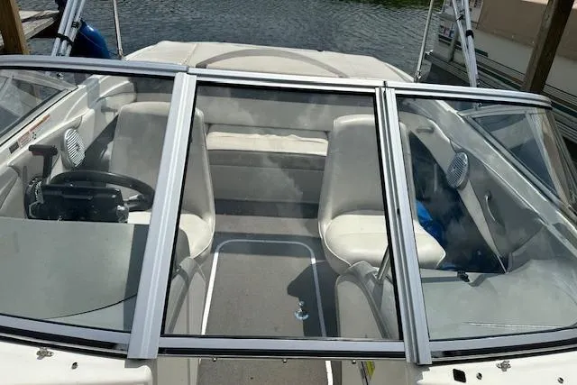 Slide: The Image of 2011 Bayliner 185 boat interior with seating and steering wheel, docked by the water. - 9