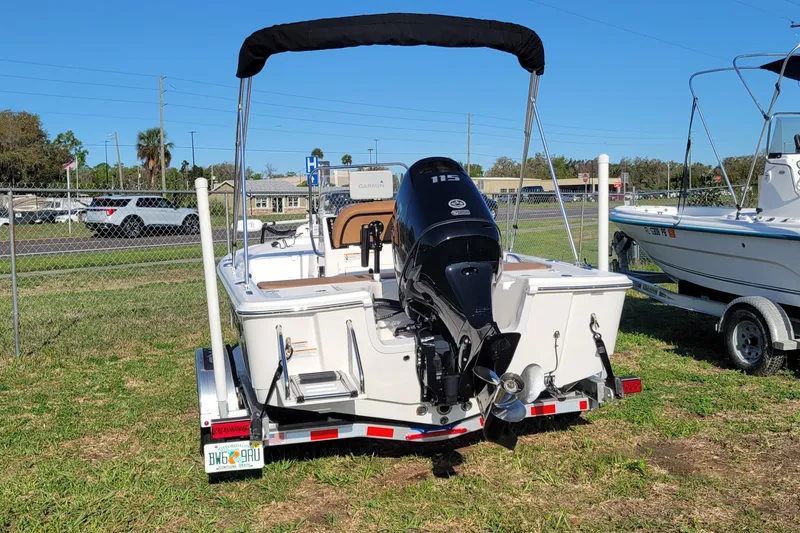 Slide: The Image of 2024 Sea Pro 172 Bay boat with outboard motor on trailer, parked on grass. - 2