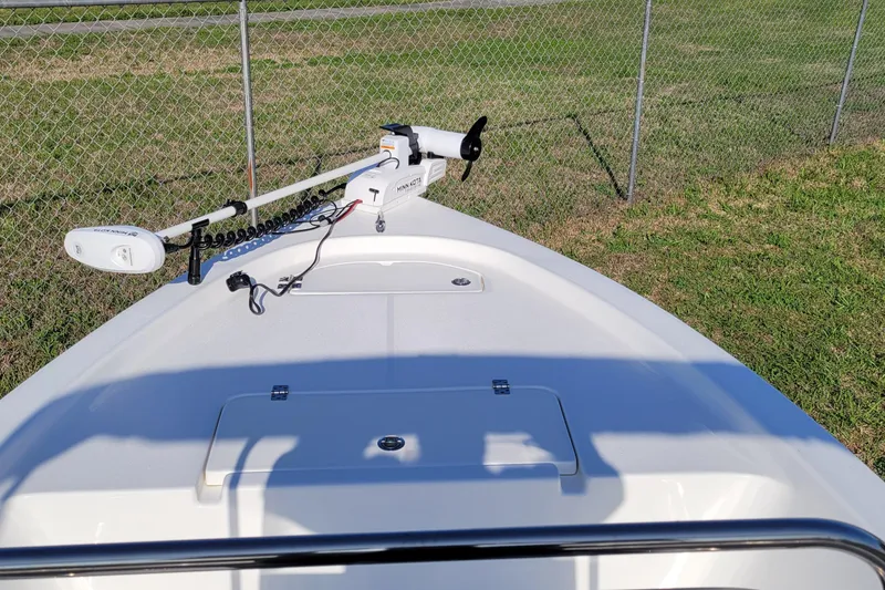 Slide: The Image of 2024 Sea Pro 172 Bay boat bow with trolling motor, parked near chain-link fence. - 5