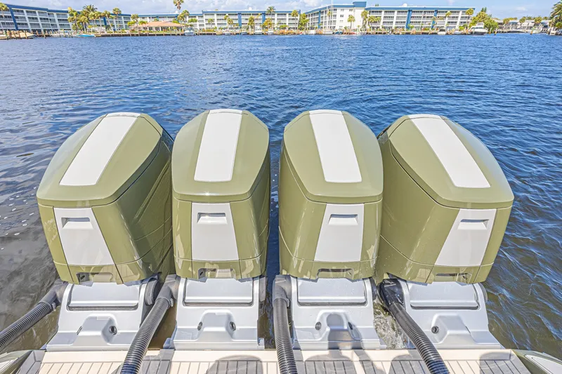 Slide: The Image of Four powerful outboard motors on a 2025 Midnight Express 52 Vitesse boat, docked by the water. - 27