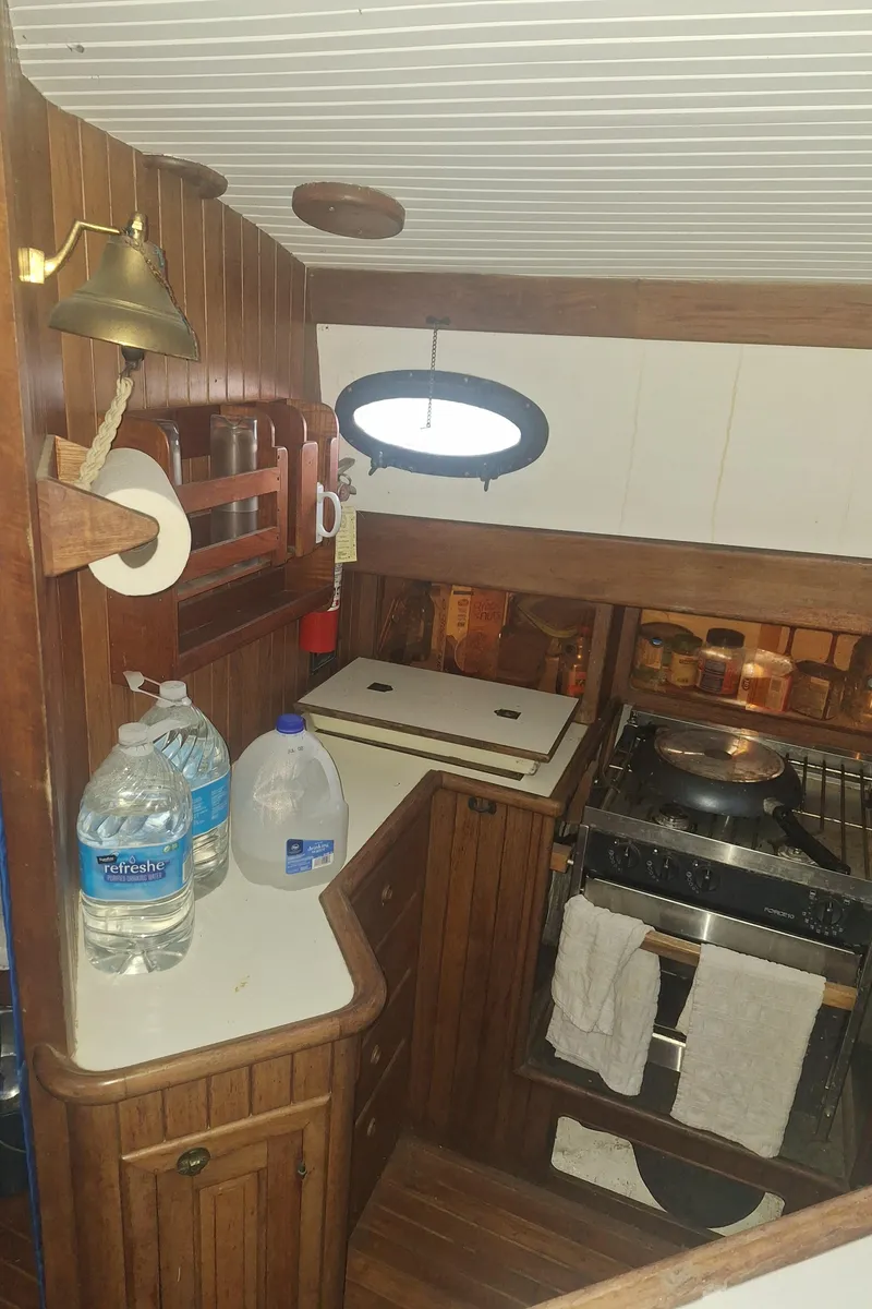Slide: The Image of 1977 Hans Christian 38 yacht galley with wood finish, stove, and water bottles. - 7
