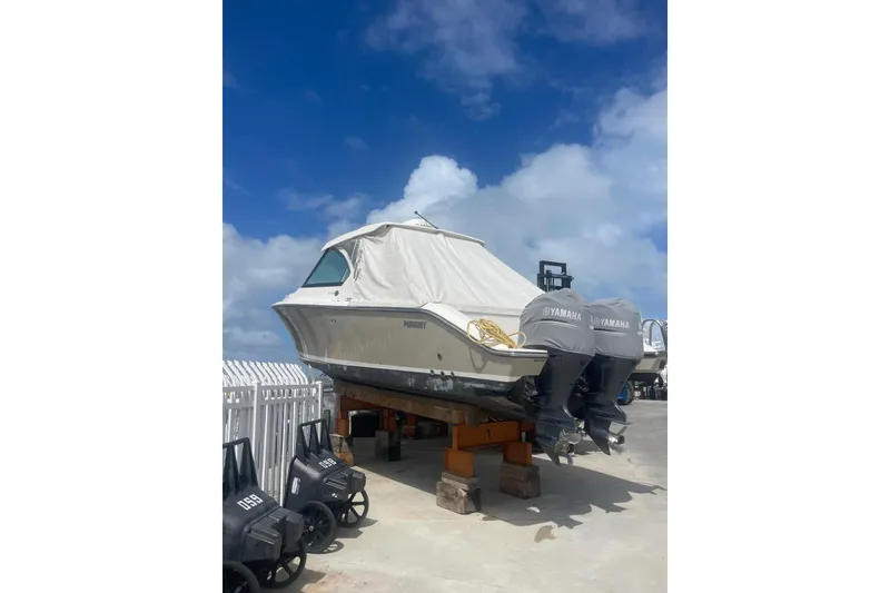 The Image of 2016 Pursuit DC 325 Dual Console boat with Yamaha engines, covered and elevated on blocks. - 0