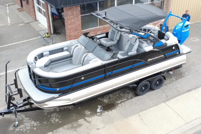 Slide: The Image of 2026 Berkshire 25RFX DC STS SPORT ARCH pontoon boat on trailer, parked outside. - 2