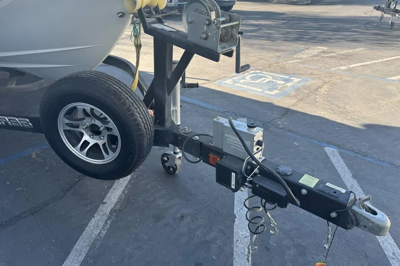Slide: The Image of Trailer hitch and wheel of a 2020 Scarab 255 Open ID boat in a parking lot. - 4