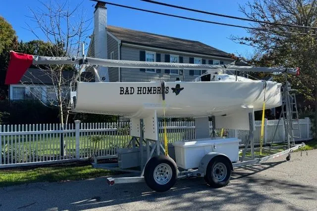 Slide: The Image of 2013 J Boats J/70 sailboat named "Bad Hombres" on a trailer in a residential area. - 1