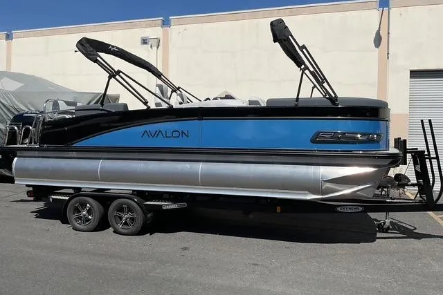 The Image of 2025 Avalon LSZ Quad Lounge Shift pontoon boat on trailer, parked outdoors. - 0