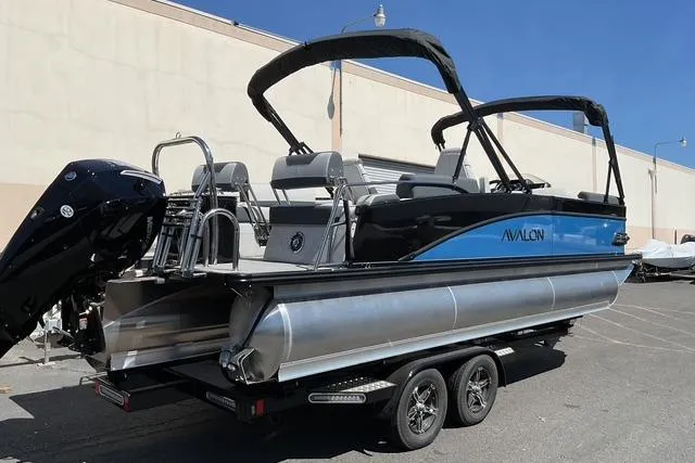 Slide: The Image of 2025 Avalon LSZ Quad Lounge Shift pontoon boat on trailer, parked outdoors. - 4