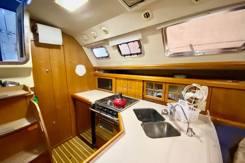 Slide: The Image of Interior of 2006 Hunter 41 Deck Salon yacht kitchen with stove, sink, and wooden cabinetry. - 12
