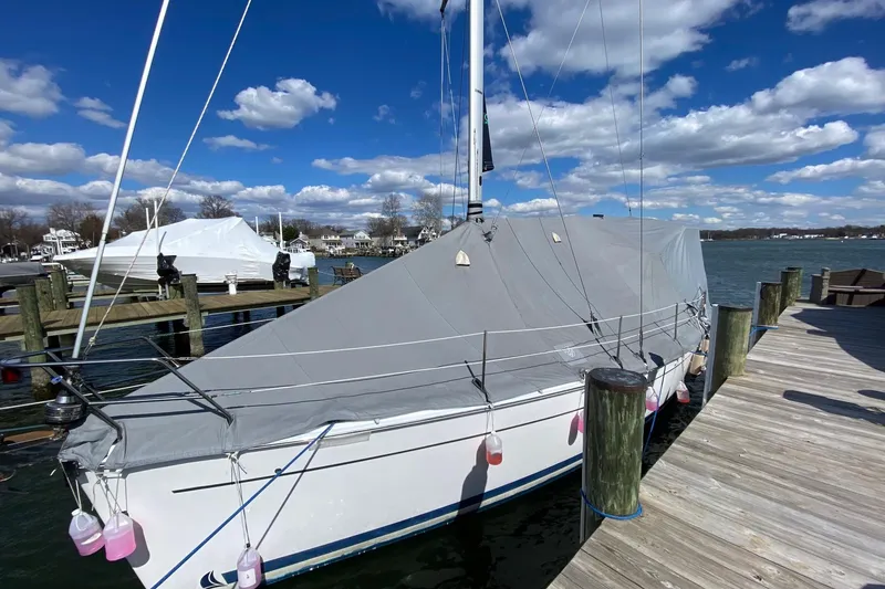 Slide: The Image of 2006 Hunter 41 Deck Salon sailboat docked, covered with a gray tarp under a blue sky. - 21