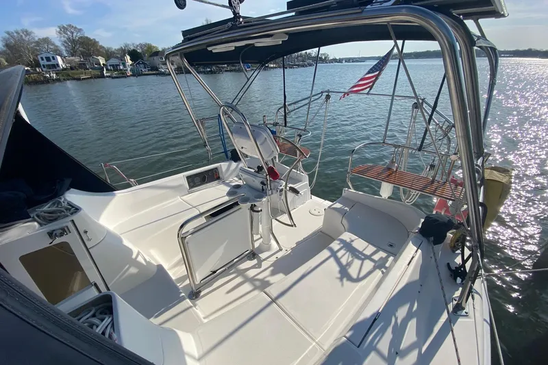 Slide: The Image of 2006 Hunter 41 Deck Salon sailboat cockpit with steering wheel, docked by waterfront homes. - 39