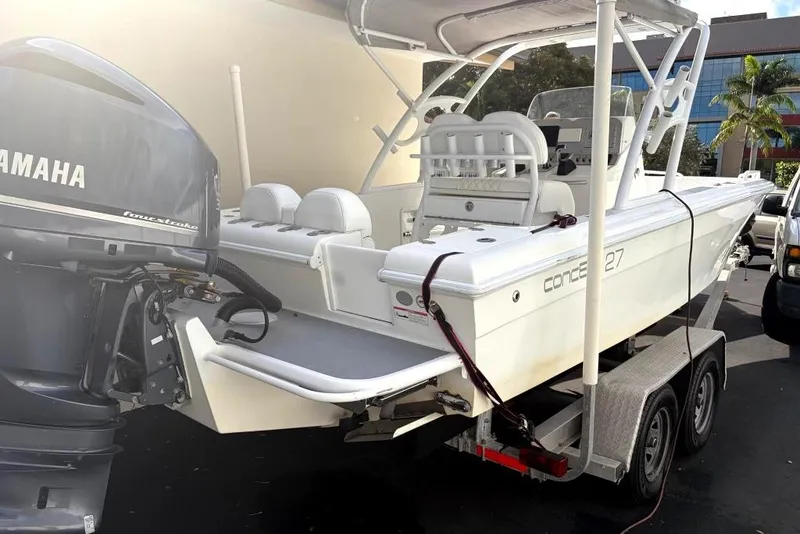 Slide: The Image of White Concept 27 boat on trailer, parked in driveway, surrounded by trees. - 3