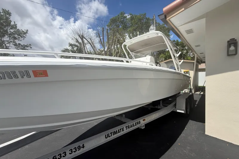 Slide: The Image of White Concept 27 boat on trailer, parked beside a building under a clear sky. - 33