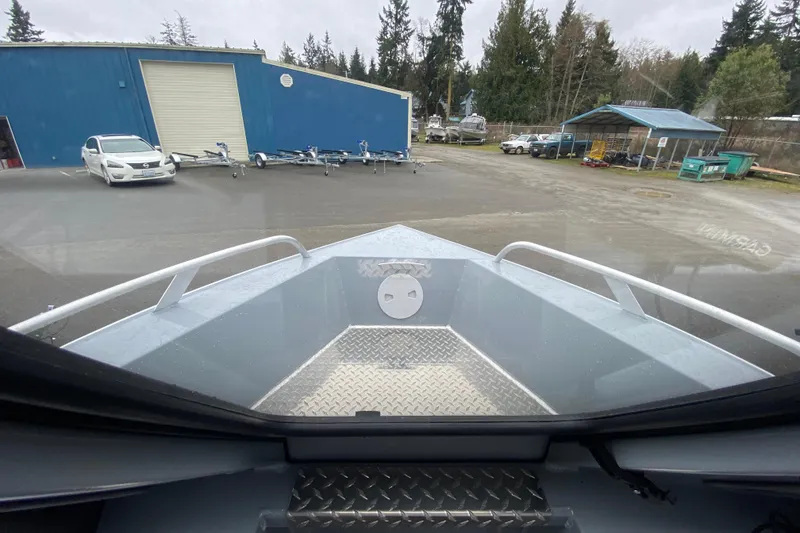 Slide: The Image of 2026 Hewescraft 200 ProV Hard Top boat at a marina with trailers and vehicles. - 11