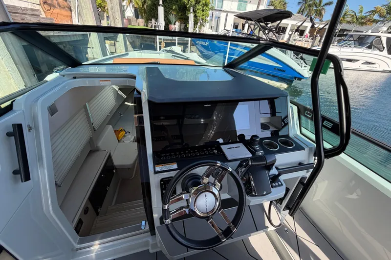 Slide: The Image of 2024 Saxdor 320 GTO cockpit with modern steering and navigation controls, docked at marina. - 13