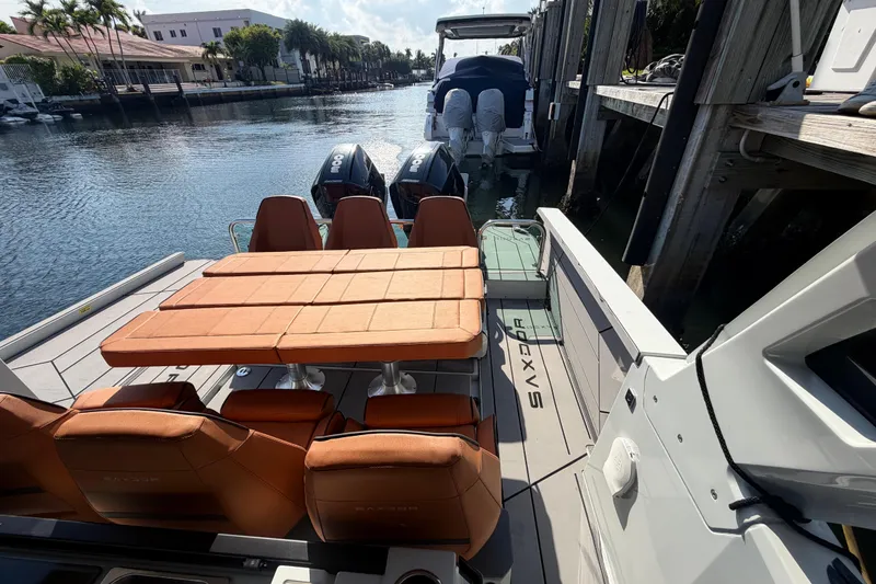 Slide: The Image of 2024 Saxdor 320 GTO boat with orange seating, docked by a scenic waterfront. - 25