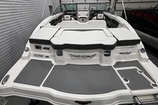 Slide: The Image of 2013 Chaparral 226 SSi boat with spacious seating and sleek design in a garage setting. - 23