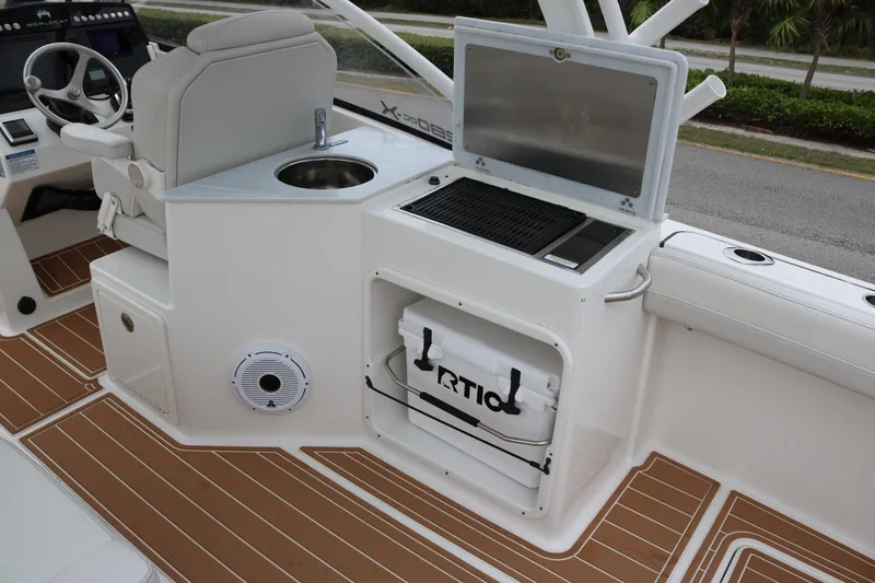 Slide: The Image of 2024 World Cat 280 DC-X boat interior with helm, sink, grill, and cooler storage. - 13