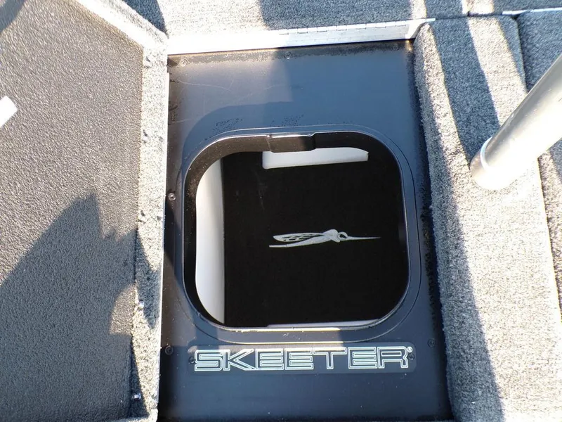 Slide: The Image of 2025 Skeeter FXR20L boat storage compartment with logo, featuring durable carpeted interior. - 24