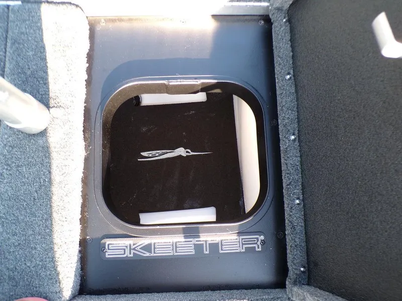 Slide: The Image of 2025 Skeeter FXR20L boat storage compartment with logo, featuring carpeted interior. - 25