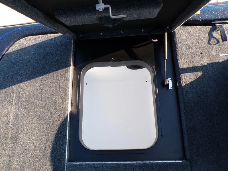 Slide: The Image of 2025 Skeeter FXR20L boat storage compartment with open hatch and carpeted interior. - 27