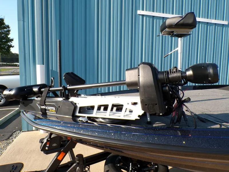 Slide: The Image of 2025 Skeeter FXR20L boat with trolling motor, parked near a blue building. - 8