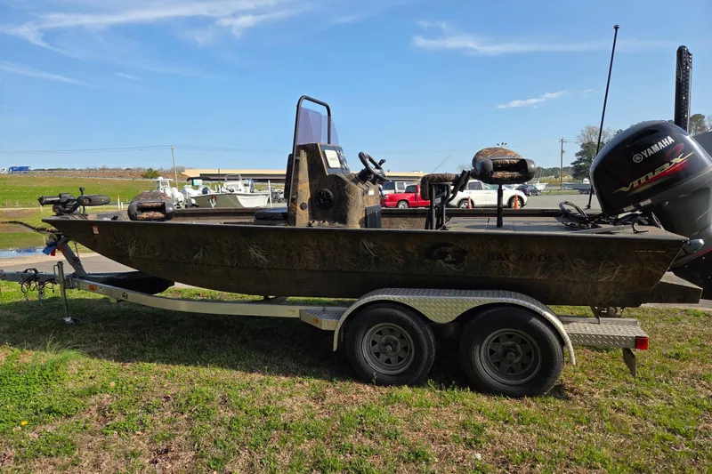 Slide: The Image of 2019 G3 Bay 20 DLX Camo boat on trailer with Yamaha motor, outdoors. - 6