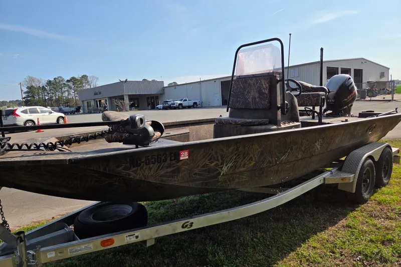 Slide: The Image of 2019 G3 Bay 20 DLX Camo boat on trailer, parked outdoors near buildings. - 7